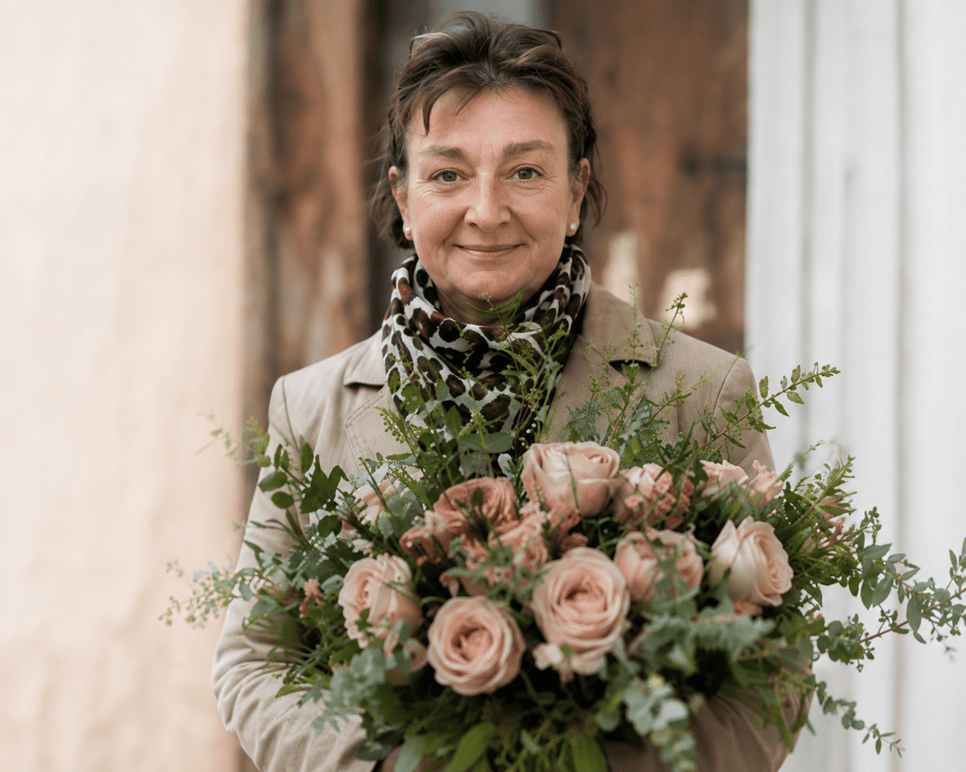Pearl and Bloom - Pearl with roses Pearl Preece holding a bouquet of blush pink roses in front of a door
